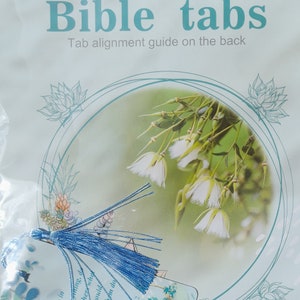May include: A set of blue bible tabs with a tassel. The tabs are decorated with a floral design and the text "Bible tabs" and "Tab alignment guide on the back".