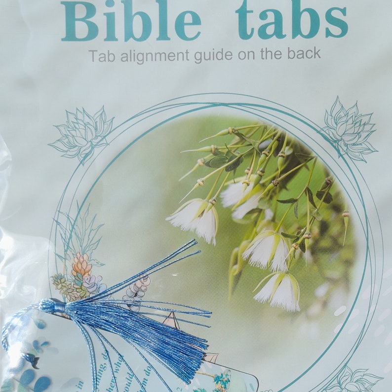 May include: A set of blue bible tabs with a tassel. The tabs are decorated with a floral design and the text "Bible tabs" and "Tab alignment guide on the back".