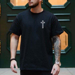 May include: A black t-shirt with a white outline of a cross on the front.