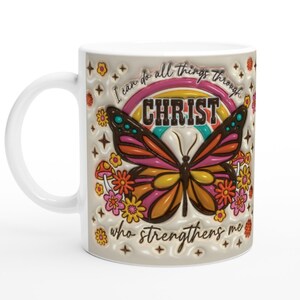 Op de afbeelding: Witte keramische mok met een kleurrijk vlinderontwerp en de tekst "Ik kan alles door CHRISTUS doen die mij sterkt".