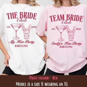 Puede incluir: Dos camisetas de gran tamaño, una blanca y otra rosa, con texto y gráficos rojos. La camiseta blanca dice "THE BRIDE Club" con "My Hen Party BARCELONA" debajo de una ilustración de cóctel. La camiseta rosa dice "TEAM BRIDE Club" con "Emily's Hen Party BARCELONA".