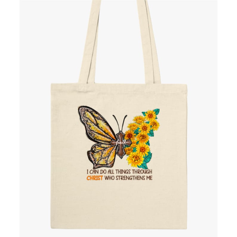 Pu&ograve; includere: Una borsa tote beige con una farfalla gialla e girasoli. La farfalla ha una croce sulle ali. Il testo "Posso fare ogni cosa in Cristo che mi fortifica" &egrave; stampato sotto la farfalla.