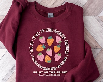 May include: Burgundy sweatshirt with a white circle design featuring strawberries and the text "LOVE-JOY-PEACE-PATIENCE-KINDNESS-GOODNESS | FAITHFULNESS-GENTLENESS-SELFCONTROL | FRUIT OF THE SPIRIT GALATIANS 5:22-23"
