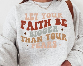 May include: A gray sweatshirt with the text "Let your faith be bigger than your fears" in a retro font with different colored letters. The text is in a light brown, red, orange, and pink color scheme.