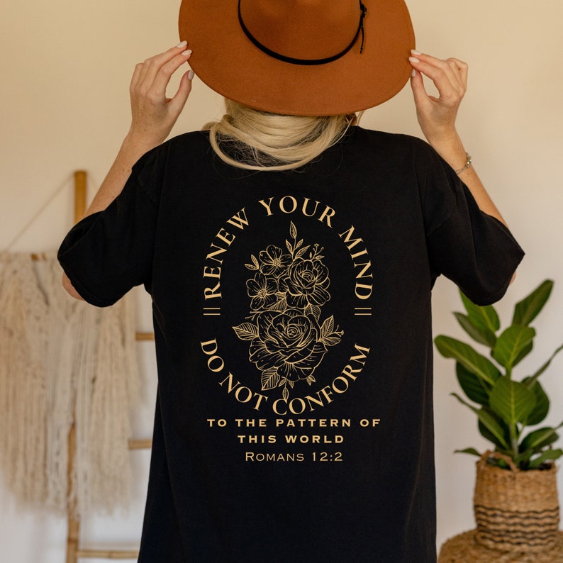 May include: Black t-shirt with a gold floral design and the text "Renew Your Mind, Do Not Conform to the Pattern of This World, Romans 12:2".