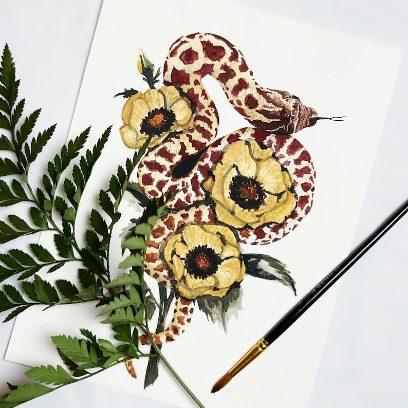 Puede incluir: Pintura acuarela de una serpiente con un cuerpo de patr&oacute;n rojo y marr&oacute;n, enroscada alrededor de tres flores amarillas con centros marrones. Las flores est&aacute;n rodeadas de hojas verdes.