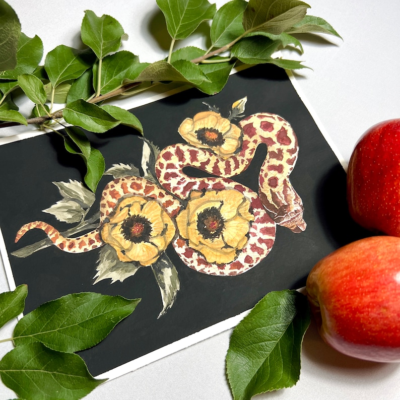 Puede incluir: Una pintura de acuarela de una serpiente envuelta alrededor de tres flores amarillas con marcas rojas y marrones sobre un fondo negro.