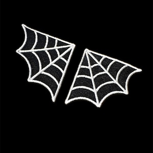 May include: Two black felt spiderweb patches with white stitching. The patches are shaped like wings and are perfect for adding a spooky touch to any project.