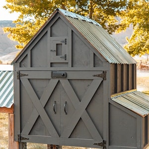 May include: A gray wooden chicken coop with a corrugated metal roof. The coop features a door with an X-shaped design, a small window, and a wire mesh enclosure. The coop is elevated on wooden posts.