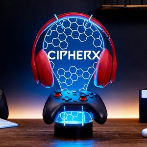 Könnte beinhalten: Eine LED-Lampe mit Gaming-Motiv, die einen roten Kopfhörer und einen schwarzen Controller zeigt. Die Lampe zeigt das Wort "CIPHERX" in Weiß auf einem blauen sechseckigen Muster. Sockel und Controller haben blaue LEDs.