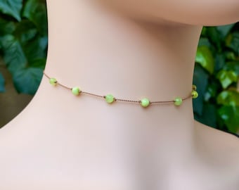 May include: A delicate choker necklace with a brown cord and light green beads. The necklace is simple and elegant, perfect for everyday wear.