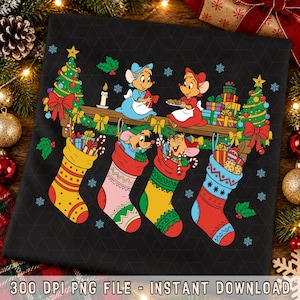 Peut inclure: Un t-shirt noir avec un motif coloré représentant quatre souris de Cendrillon célébrant Noël. Le design comprend deux souris sur une cheminée en bois, quatre chaussettes de Noël à motifs remplies de cadeaux, deux sapins décorés et des flocons.