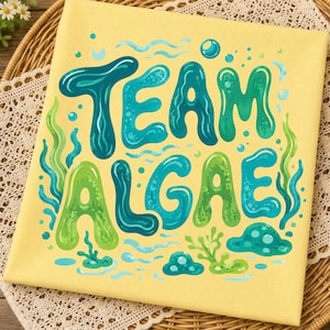 May include: A square yellow fabric featuring the text "TEAM ALGAE" in large, bubbly, blue and green letters. The design includes illustrations of aquatic plants, bubbles, and wavy lines surrounding the text, creating an underwater theme.