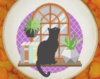 May include: A black cat sits on a shelf with books and plants, looking out a window. The scene is framed in a round embroidery hoop, surrounded by orange flower petals on a white wood background. The text "ORANGE POTATO Design" is visible in the top center of the image.