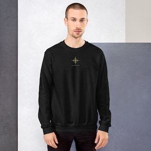 May include: A black sweatshirt with a yellow crosshair design on the front.