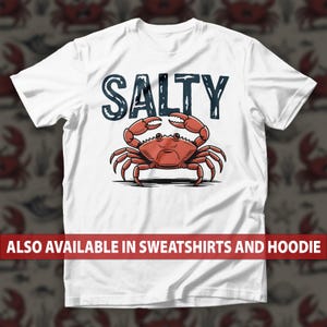 May include: White t-shirt featuring a red crab illustration with the word "SALTY" in dark blue above it. The text "ALSO AVAILABLE IN SWEATSHIRTS AND HOODIE" is displayed in a red banner at the bottom.