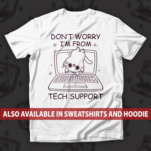 May include: White t-shirt with a black graphic of a cat hanging upside down from a laptop screen. Text reads "DON'T WORRY I'M FROM TECH SUPPORT." Additional text at the bottom says "ALSO AVAILABLE IN SWEATSHIRTS AND HOODIE."