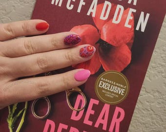 May include: A book titled Dear Debbie by Freida McFadden with a dark red cover featuring a large red flower illustration. The cover includes the text #1 New York Times Bestselling Author and a gold Barnes & Noble Exclusive sticker with special content.