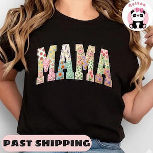 Puede incluir: Camiseta negra con la palabra "MAMA" en letras grandes con estampado floral. Las letras están rellenas de varios diseños florales coloridos. La camiseta es de cuello redondo.