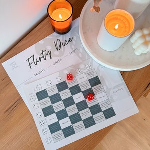 May include: A flirty dice game with a grid of questions and dares. The game includes two red dice and a card with the words "Flirty Dice", "Truths", "Dares", and "Shots".