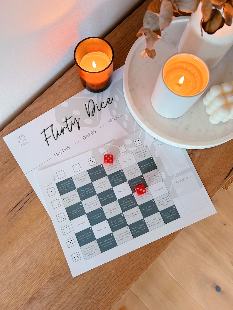 May include: A flirty dice game with a grid of questions and dares. The game includes two red dice and a card with the words "Flirty Dice", "Truths", "Dares", and "Shots".