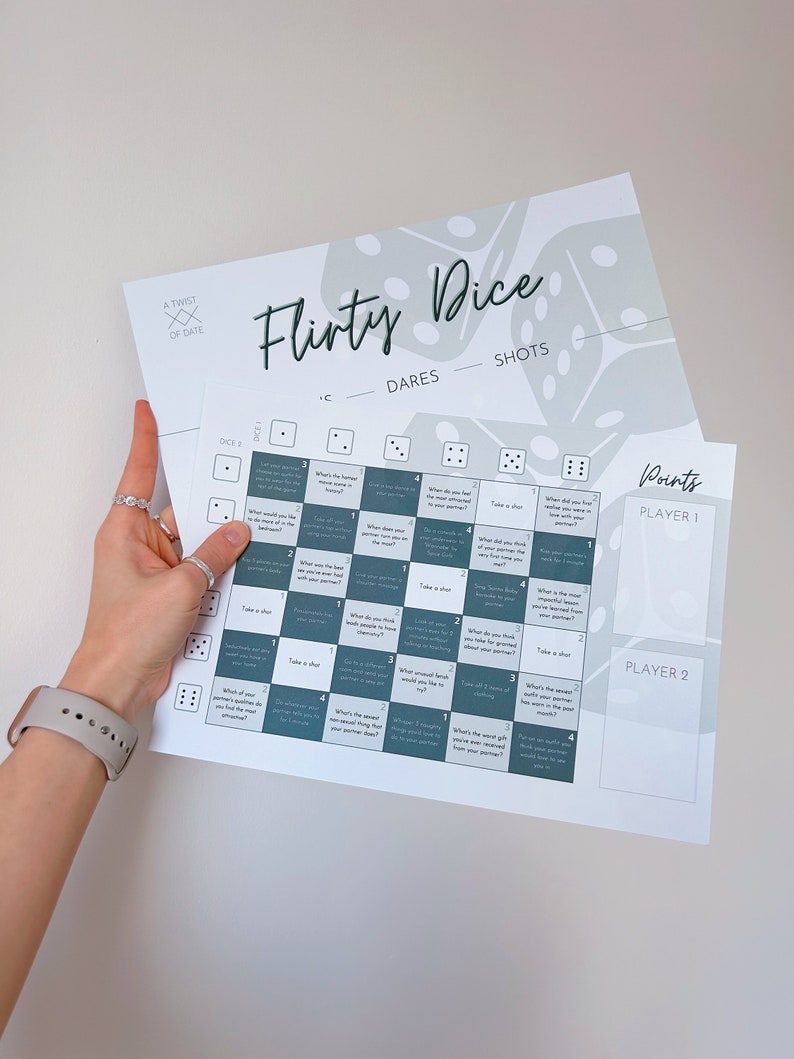 May include: A Flirty Dice game with a white background and green and gray dice. The game includes dares and shots. The game is designed for two players. The game includes a points section for each player.