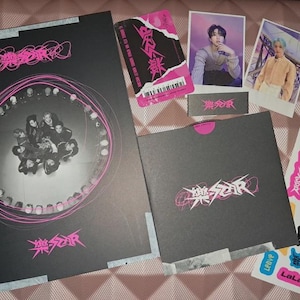 Puede incluir: Una colección de merchandising de K-pop con un álbum negro grande con una foto grupal y detalles en rosa, junto con tarjetas fotográficas, pegatinas y un pequeño álbum gris. La portada del álbum incluye el texto "樂STAR".