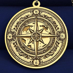 Può includere: Una collana con ciondolo circolare color oro caratterizzata da un design inciso a rosa dei venti. Il centro mostra un ago dettagliato a forma di stella che punta verso i punti cardinali N, S, E e O, circondato da un bordo decorativo.