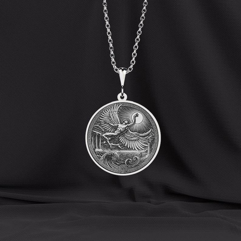 May include: A silver pendant necklace featuring a circular pendant with a detailed relief of a winged figure reaching towards a sun. The pendant is suspended from a delicate chain. The design includes architectural elements and waves.