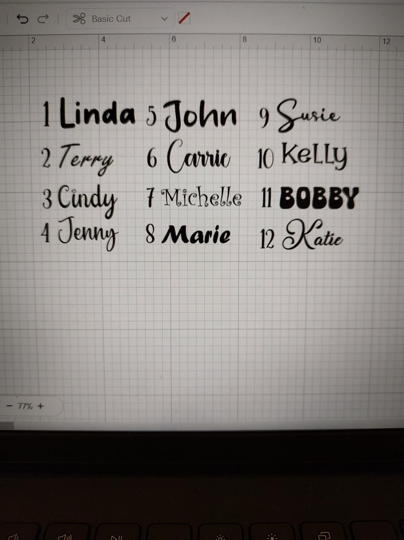 May include: A digital screen shows a grid with the names "Linda", "Terry", "Cindy", "Jenny", "John", "Carrie", "Michelle", "Marie", "Susie", "Kelly", "BOBBY", and "Katie" in black cursive font, each numbered.
