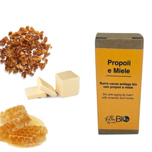 Può includere: Una scatola di cartone marrone con un'etichetta gialla che recita "Propoli e Miele" e "Burro cacao antiage bio con propoli e miele". L'etichetta riporta anche "Bio anti-aging lip balm with propolis and honey" e "Filler BIO by nature". La scatola è su uno sfondo bianco. Ci sono anche immagini di favo, burro e propoli.