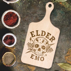May include: A wooden cutting board with a handle, featuring a skull with lightning bolts and the text "ELDER EMO".