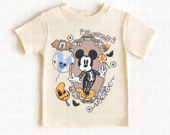 May include: Cream-colored t-shirt featuring a Halloween-themed Mickey Mouse design. The graphic includes Mickey in a skeleton costume, surrounded by spooky elements like bats, candy corn, and the text "Main Street Scare".