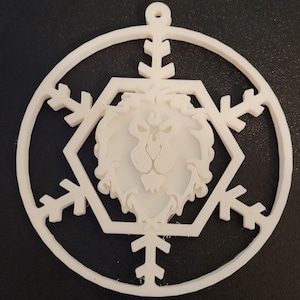 Peut inclure: Ornement de Noël en plastique blanc avec un motif de flocon de neige et une tête de lion au centre.