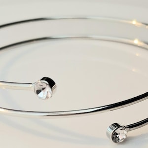 May include: A silver double-wrap bangle bracelet with two clear crystal accents.