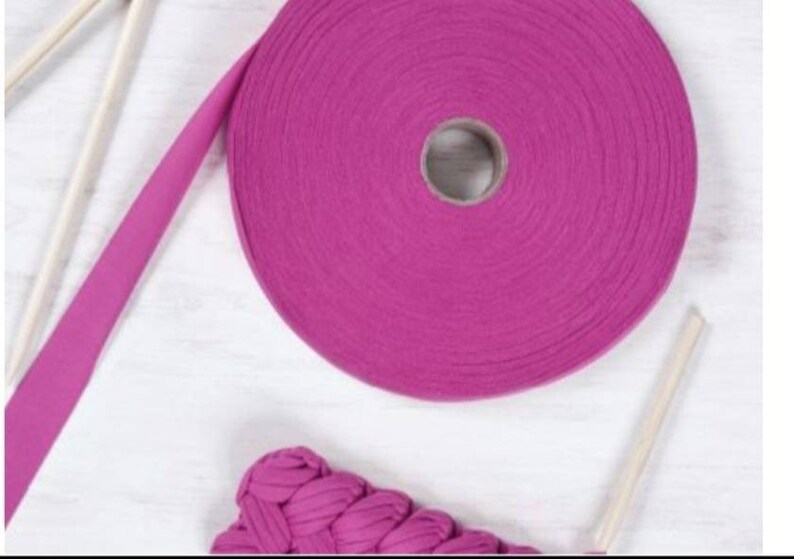 May include: A roll of pink cotton rope yarn with a wooden dowel rod. The yarn is wound around a cardboard tube.