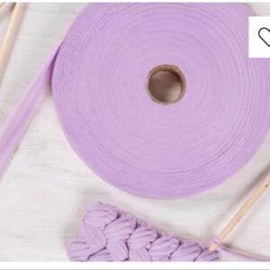 May include: A roll of lavender colored cotton rope with a wooden knitting needle and a crocheted piece of fabric.