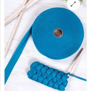 May include: A roll of teal blue fabric yarn with wooden knitting needles and a crocheted teal blue fabric pouch.