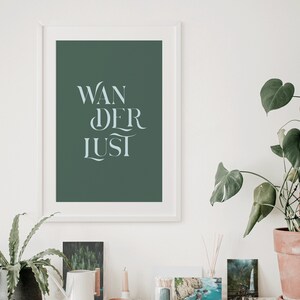 May include: A white framed print with a dark green background and the text "WANDERLUST" in a light blue font.