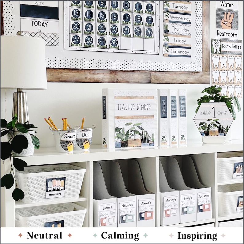 May include: A white shelf unit with various classroom organization supplies. The shelf is labeled with the words "Neutral", "Calming", and "Inspiring". There are white bins labeled with the words "markers", "Liam's Book Bin", "Naomi's Book Bin", "Alexa's Book Bin", "Marley's Book Bin", "Emily's Book Bin", and "Jackson's Book Bin". There are also two small metal containers labeled "Sharp" and "Dull".