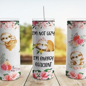 Puede incluir: Tres vasos de acero inoxidable con fondo blanco y diseños florales. El vaso del centro tiene el texto "No soy perezoso, soy eficiente en energía" y un perezoso de dibujos animados con una corona de flores. Los otros dos vasos tienen perezosos de dibujos animados con flores.