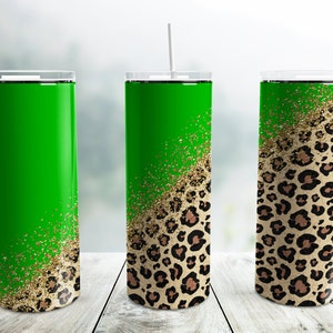 Pode incluir: Três copos de aço inoxidável com um design de estampa de leopardo verde e dourado com glitter. Os copos são todos do mesmo tamanho e forma, e estão todos em pé sobre uma superfície de madeira.