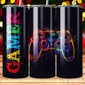 May include: Three stainless steel tumblers with a black background. The tumbler on the left has the word "GAMER" in colorful letters. The tumblers in the middle and right have a colorful illustration of a video game controller.