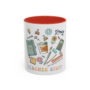 May include: White ceramic mug with a red interior, decorated with colorful illustrations of school supplies and the words "TEACHER STUFF." The design includes a notebook, coffee cup, glasses, and a calculator.