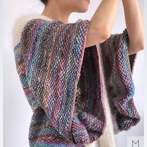 Puede incluir: Un cárdigan de punto multicolor con ribete blanco. El cárdigan tiene un corte holgado y un diseño amplio y fluido. El cárdigan está hecho de un hilo suave y texturizado.