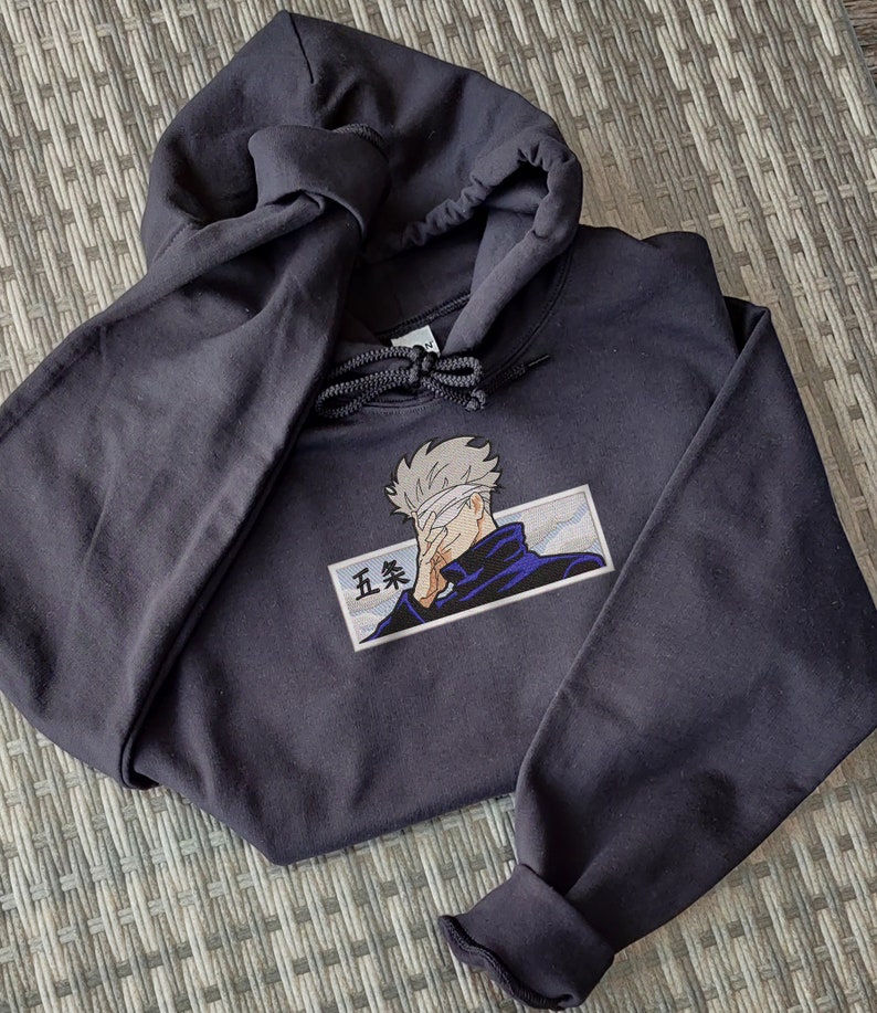 May include: A black hooded sweatshirt with a white and blue embroidered image of a character with a blindfold and the text "五条" on the front.
