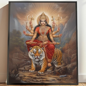 May include: A colorful painting of a Hindu goddess, Durga, riding a tiger. She is depicted with multiple arms, holding weapons and wearing a red and gold sari. The background is a mountainous landscape with a waterfall.