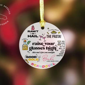 May include: Round white ornament with colorful text and illustrations. The text reads "Rawt in Hail", "It's not about the pasta!", "Raise your glasses high, this one's for you tonight", "Good as Gold", "Babe I was born cool", "Scandoval", "Rob hung a TV on the wall in less than seven minutes".