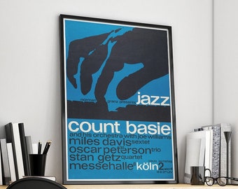 May include: A framed poster with a black border featuring a blue and black design. The poster advertises a jazz concert with the text "Jazz" and the names "Count Basie," "Miles Davis," and "Oscar Peterson." The poster is displayed on a wooden desk.