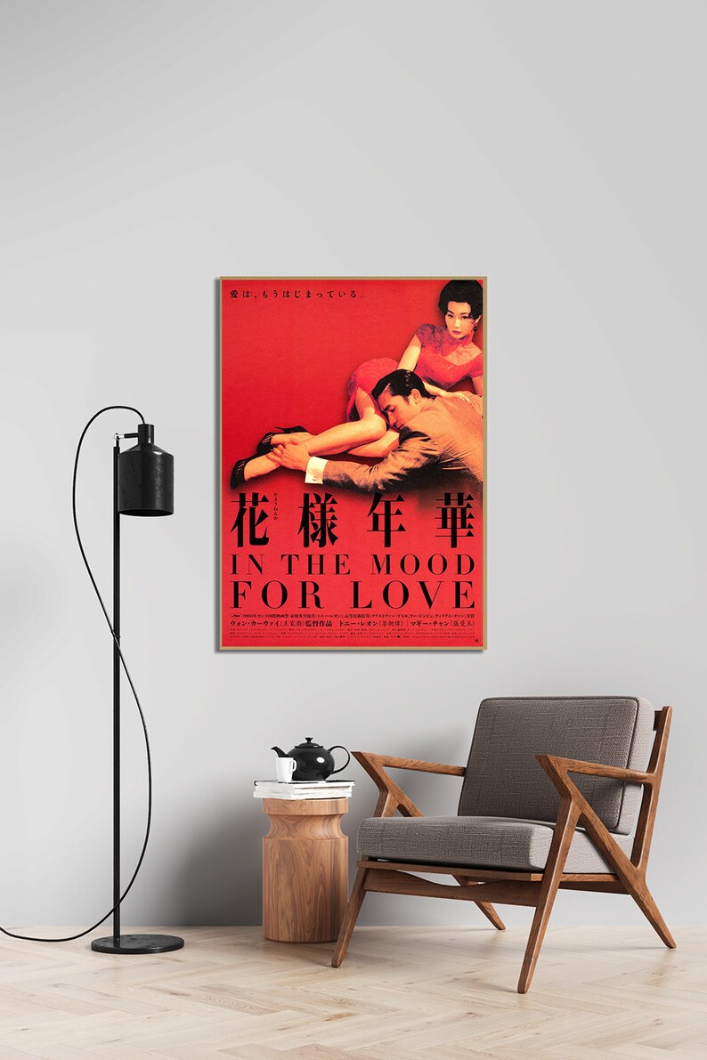 Puede incluir: Un p&oacute;ster de pel&iacute;cula rojo y dorado para la pel&iacute;cula "In the Mood for Love" que presenta a una pareja en un abrazo rom&aacute;ntico. El p&oacute;ster incluye el t&iacute;tulo de la pel&iacute;cula en ingl&eacute;s y japon&eacute;s, as&iacute; como los nombres del director y los actores.